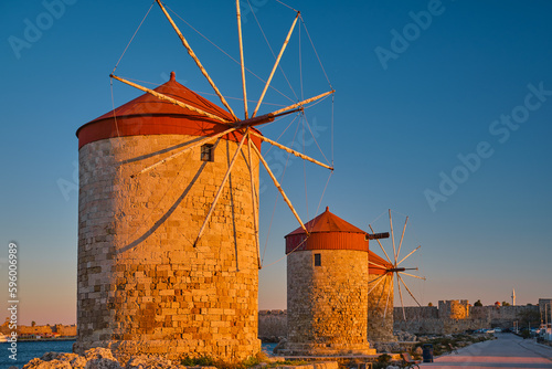 Windmills on the shore of the bay during sunset, in the city of Rhodes on the island of Rhodes of the island of the Dodecanese archipelago, Europe.Vacation and popular travel destination
