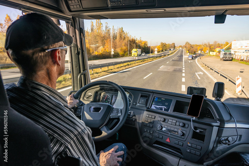 View from inside the cab of the truck. The truck is driving down the road. Car transport.