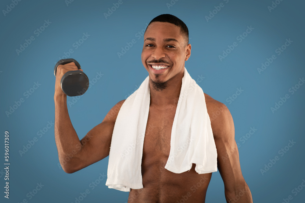 Cheerful athletic black man exercising with barbell on blue