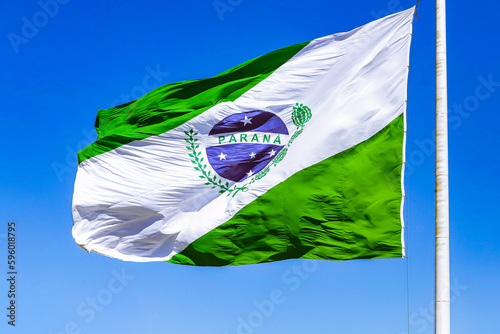 Flag of Paraná, state located in the southern region of Brazil, country located in the American continent, on a blue sky background, fluttering on a relatively rusty flagpole.