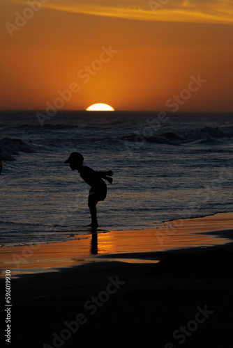Human silhouette with the sun setting in the sea in the background. Concepts of fun and vacation.
