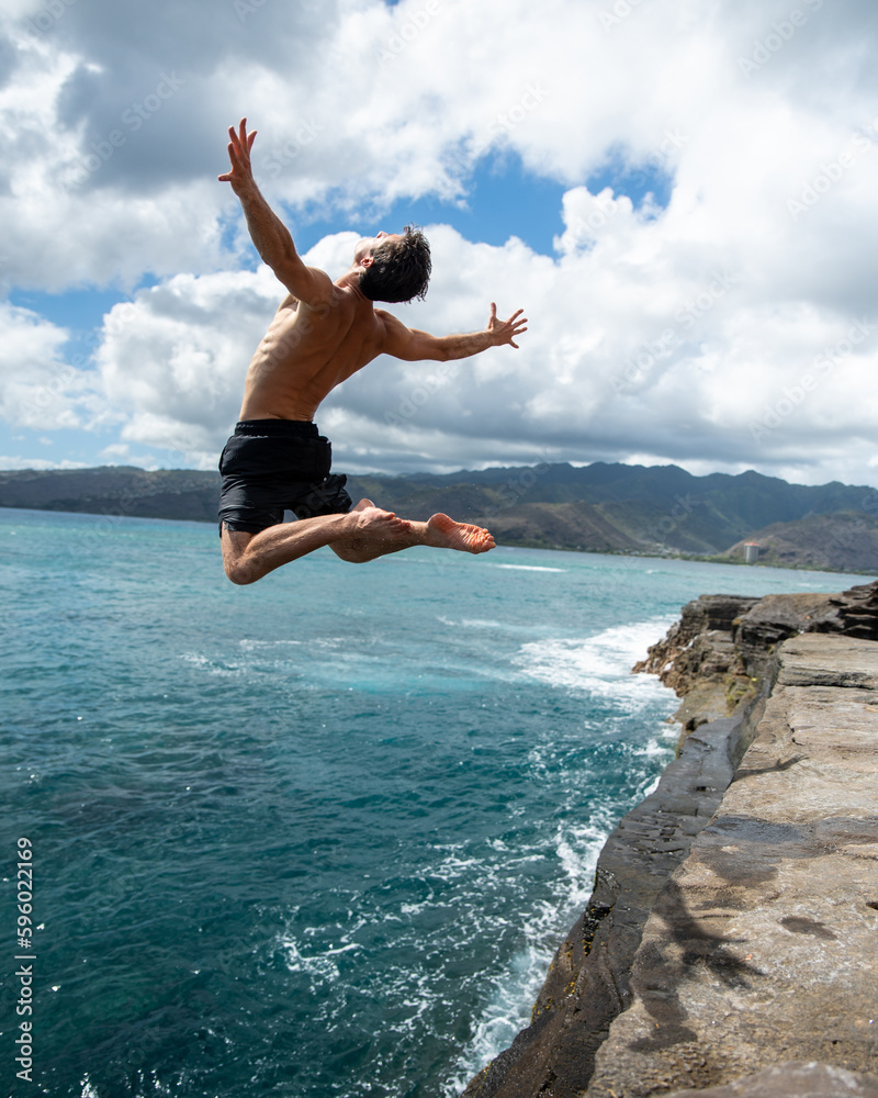 Man cliff jumping off Spitting Cave on Oahu, Hawaii. High quality photo
Man cliff jumping off Spitting Cave on Oahu, Hawaii. High quality photo