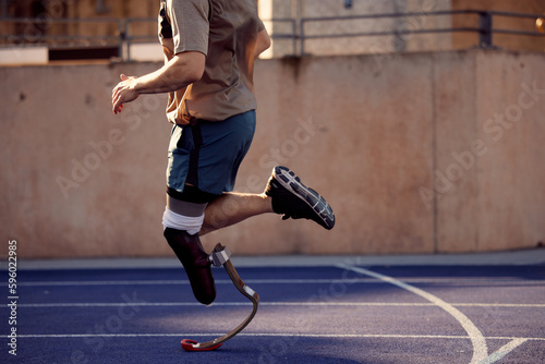 Fit man with a prosthetic blade running on an outdoor track photo