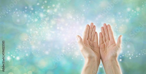 Reiki Healer channeling high resonance Healing Energy - female open palm hands against a pastel green sparkling bokeh effect background with space for  messages or business card template
