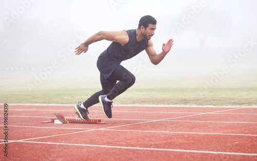 The race is on. Full length shot of a handsome young male athlete running on an outdoor track.