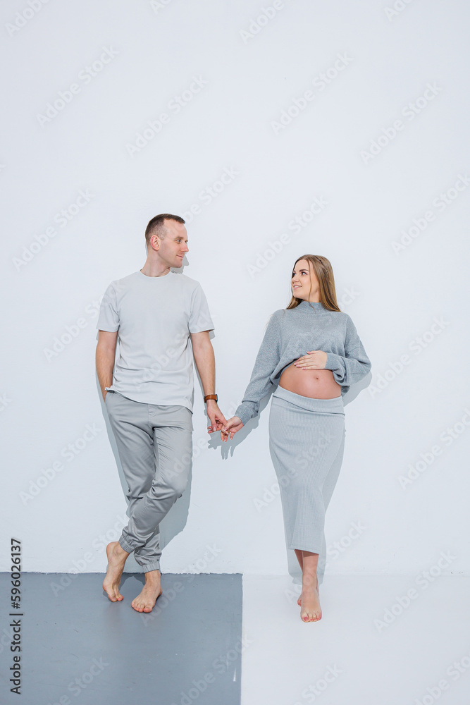 A young happy married couple is happy about pregnancy and hugging on a white background. A happy husband and wife are pregnant and expecting a child. A young happy married couple is happy about pregnancy and hugging on a white background. A happy husband and wife are pregnant and expecting a child.