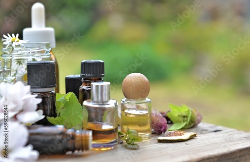 bottles of essential oil with plant and flower  on a wooden table in garden