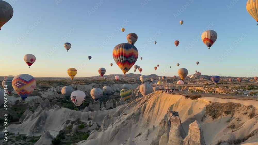 balloons floating in Cappadocia at sunrise on a clear day with sunshine and blue sky