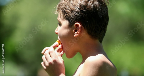 Child boy eating peach fruit in outdoor nature