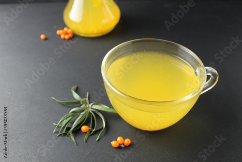 Sea buckthorn tea yellow lemonade from sea buckthorn iago on a black background in a glass cup. Vitamin C. Hot Autumn Drinks photo