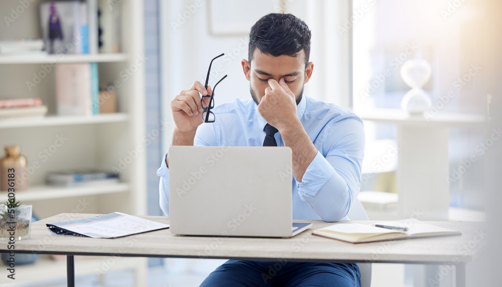 Perhaps its time for a change. a young businessman experiencing a headache at work. Perhaps its time for a change. a young businessman experiencing a headache at work.