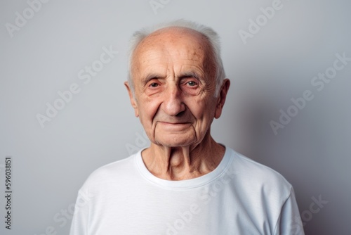 Portrait of an elderly man in a white T-shirt on a gray background