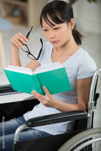 smiling young woman in wheelchair reading a book