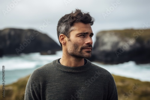 Portrait of a handsome young man looking away while standing by the ocean