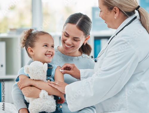 Shes not afraid to get her routine vaccine. a doctor using a cotton ball on a little girls arm while administering an injection in a clinic.