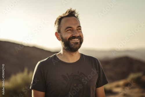 Portrait of a handsome young man smiling and looking at the camera while standing in a desert