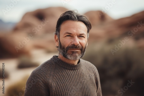 Portrait of mature man with grey beard and mustache looking at camera in the desert