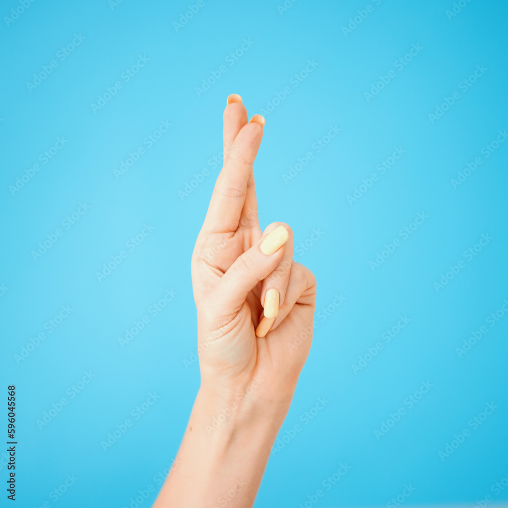 I hope I get it. Studio shot of an unrecognisable woman crossing her fingers against a blue background.