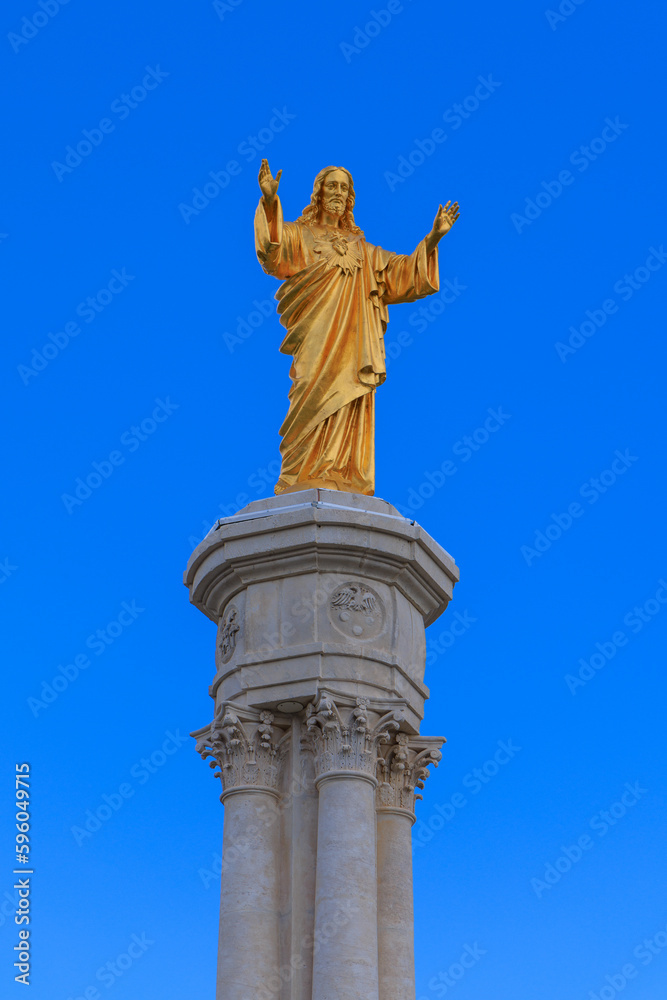Golden Christ statue on blue sky- Fatima in Portugal