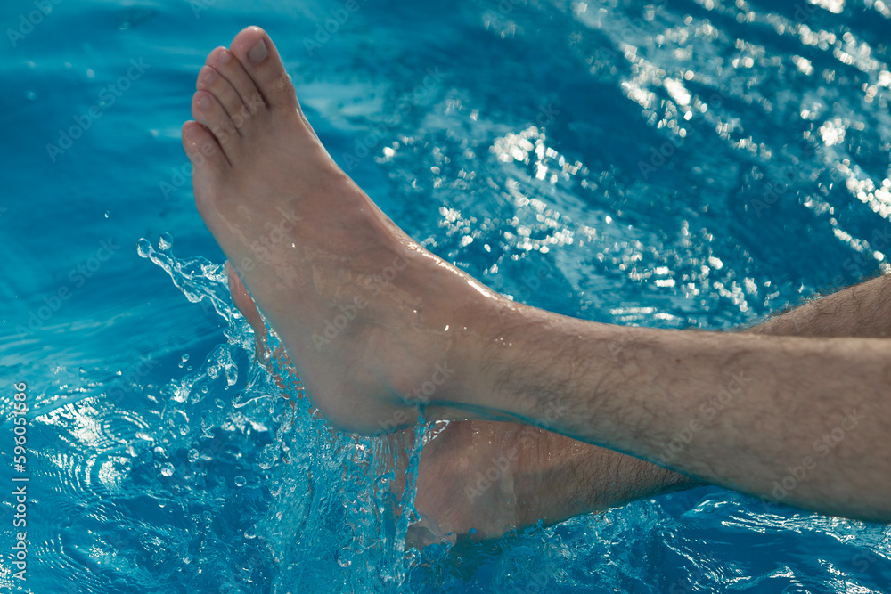 Feet of man in the water of a swimming pool