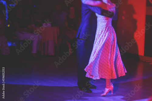 Couples dancing traditional latin argentinian dance milonga in the ballroom, tango salsa bachata kizomba lesson in the red and purple lights, dance school class festival
