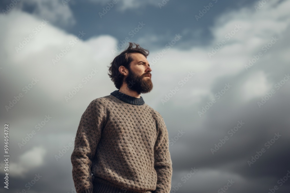 Portrait of a bearded man in a sweater on a cloudy sky background Portrait of a bearded man in a sweater on a cloudy sky background
