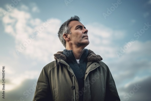 Handsome middle-aged man in winter coat looking away while standing outdoors