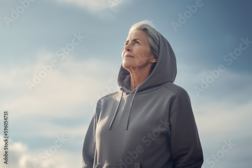 Portrait of senior woman in sportswear against cloudy sky.