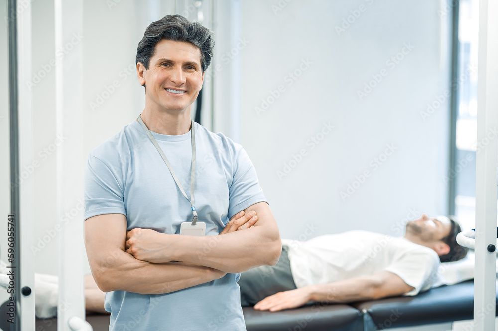 Fototapeta premium Dark-haired male physical therapist looking confident and smiling
