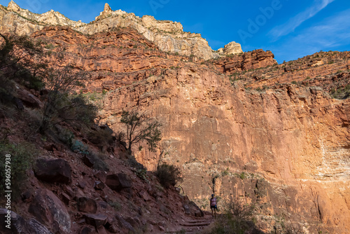 Woman hiking along Bright Angel trail with panoramic aerial overlook of South Rim of Grand Canyon National Park, Arizona, USA, America. View on massiv cliffs, rock formations and steep stone walls © Chris