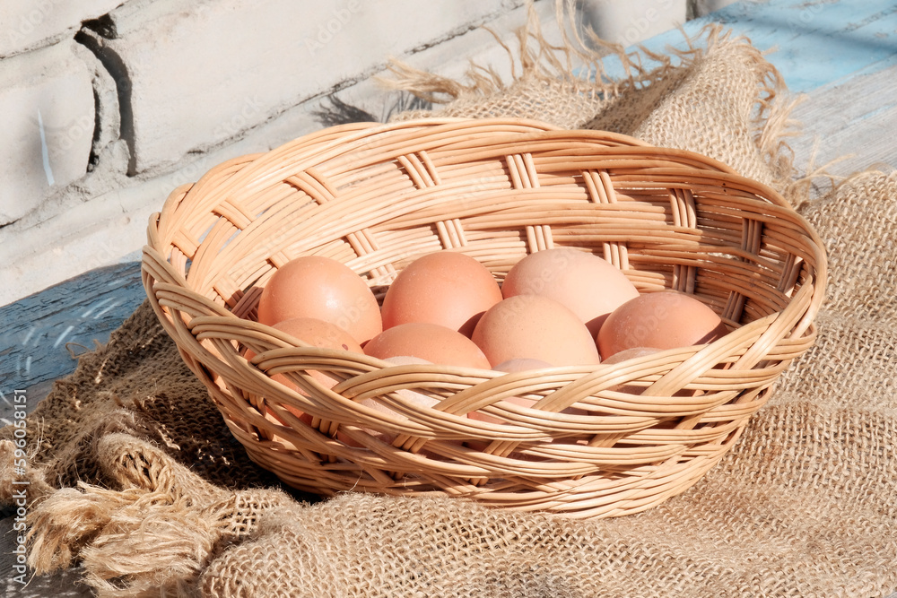 Brown large eggs in a wicker wooden basket on a retro background on a sunny day. The concept of a farmer's natural product Increasing the price of the product.