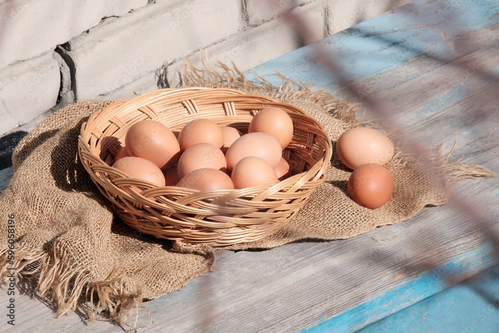 Brown large eggs in a wicker wooden basket on a retro background on a sunny day. The concept of a farmer's natural product Increasing the price of the product.