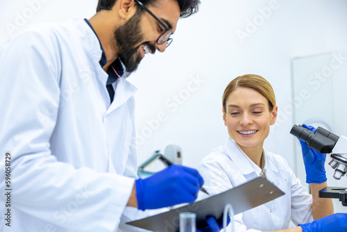 Woman and man scientists in lab coat making notes after doing sample test in laboratory.