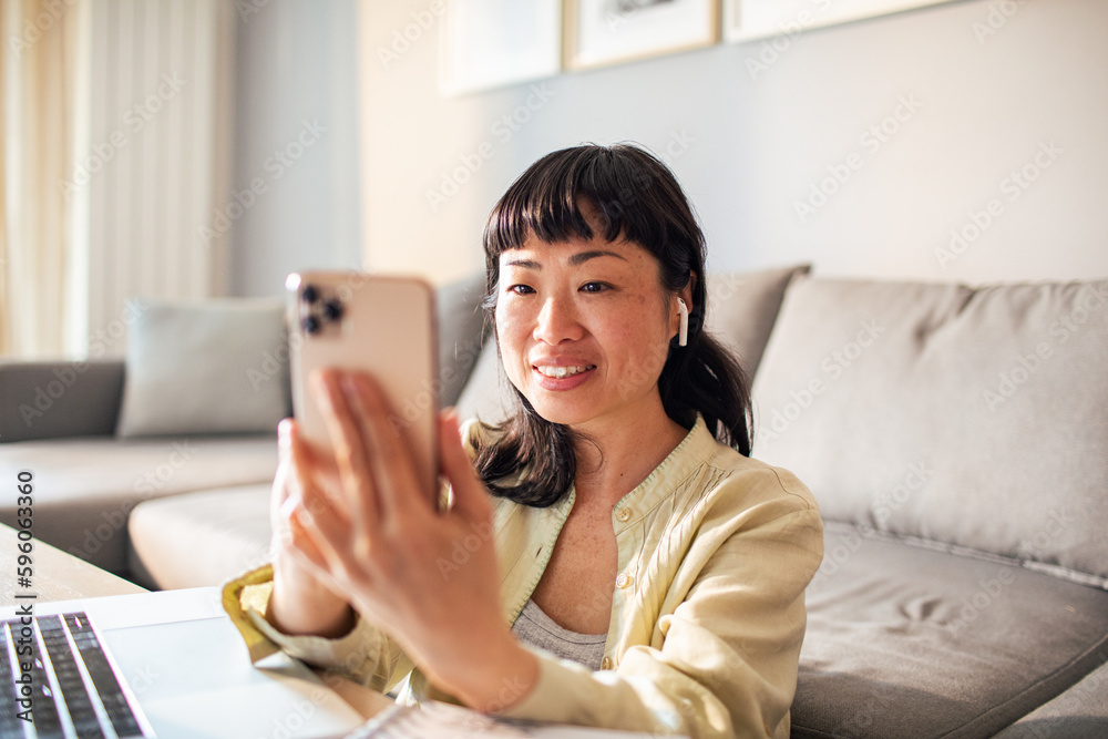 Young Japanese woman using a smart phone in the living room Young Japanese woman using a smart phone in the living room