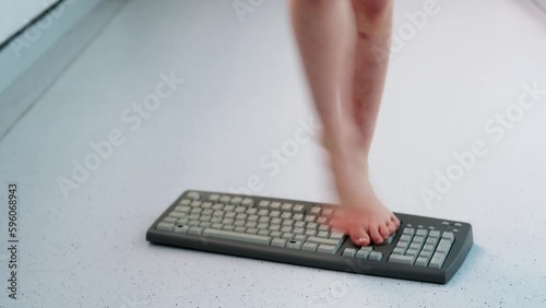 child stands, jumps, dances with his feet on computer keyboard, presses buttons, little vandal, bully plays with gadget, bullying concept, spoils technology until parents can see