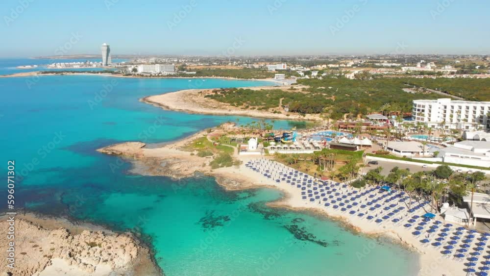 Ayia Napa, Cyprus - 15th april, 2023: aerial fly over Luxury hotel buildings with pools by beach with island greenery panorama. White sand most famous in Cyprus - Nissi beach Ayia Napa, Cyprus - 15th april, 2023: aerial fly over Luxury hotel buildings with pools by beach with island greenery panorama. White sand most famous in Cyprus - Nissi beach