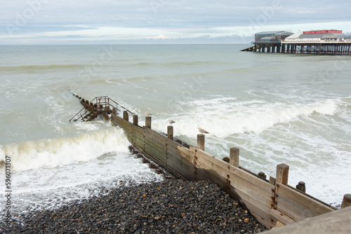 Breakwater, wooden groyne stretches out into the sea preventing the waves from eroding the beach by longshore drift. photo