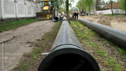 Wallpaper Mural A close-up of a large plastic water pipe prepared to be buried underground to carry out urban communications. Water supply and sewerage system of the city. 
Utilities carry out repairs Torontodigital.ca