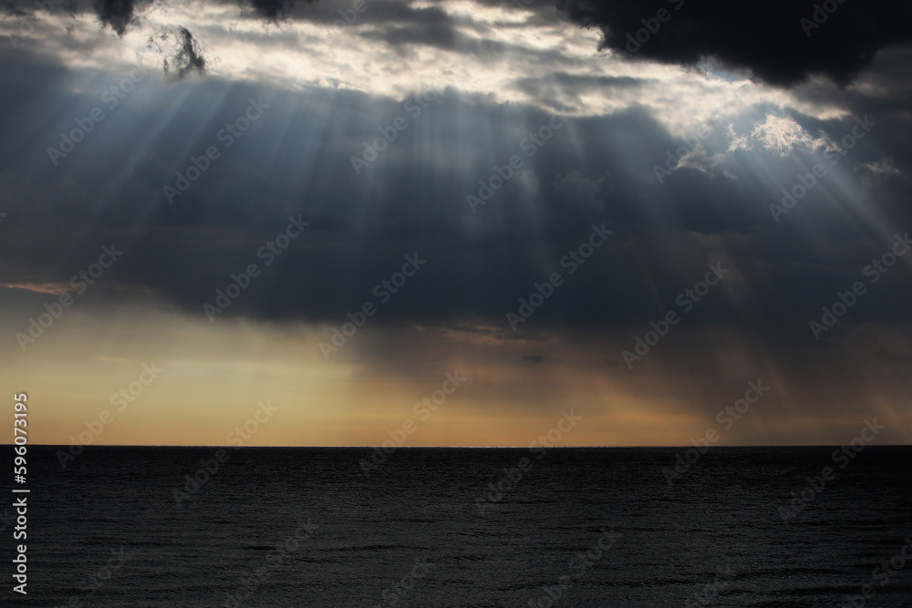 Sunset over the sea with sun rays in a black cloud