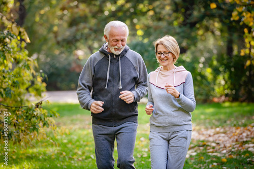 Smiling senior couple jogging in the park. Sports activities for elderly people © lordn