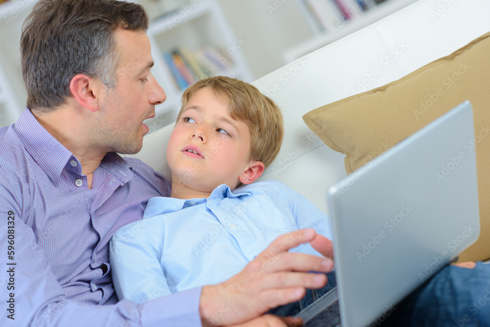 Man and child at home, holding laptop Man and child at home, holding laptop