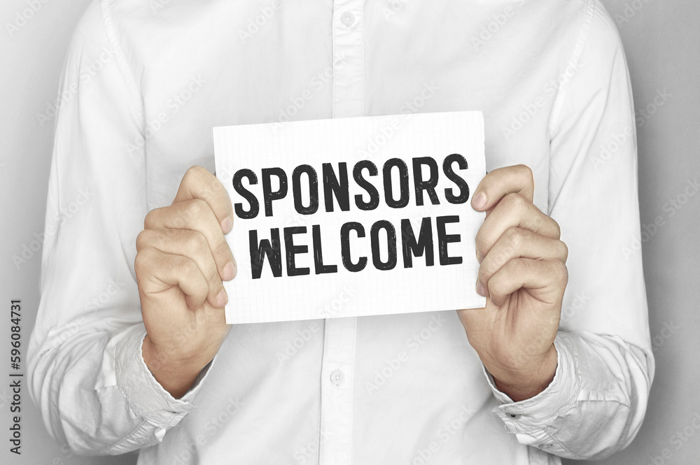Man holding a paper card with text SPONSORS WELCOME Man holding a paper card with text SPONSORS WELCOME