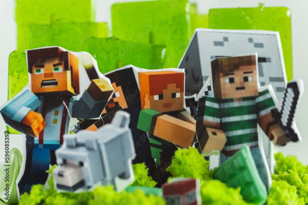 Fototapeta premium KYIV, UKRAINE - April 02: Birthday cake for a fan of Minecraft game on white background. Cake for a gameboy decorated with edible green grass and square caramel candies