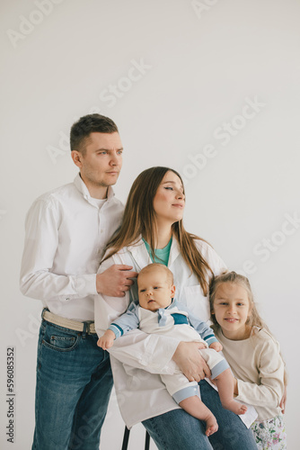 Happy family of mother, father and two kids, wearing casual clothes on white background.