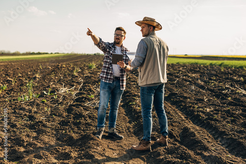 Two farmers standing in the field and using a digital tablet