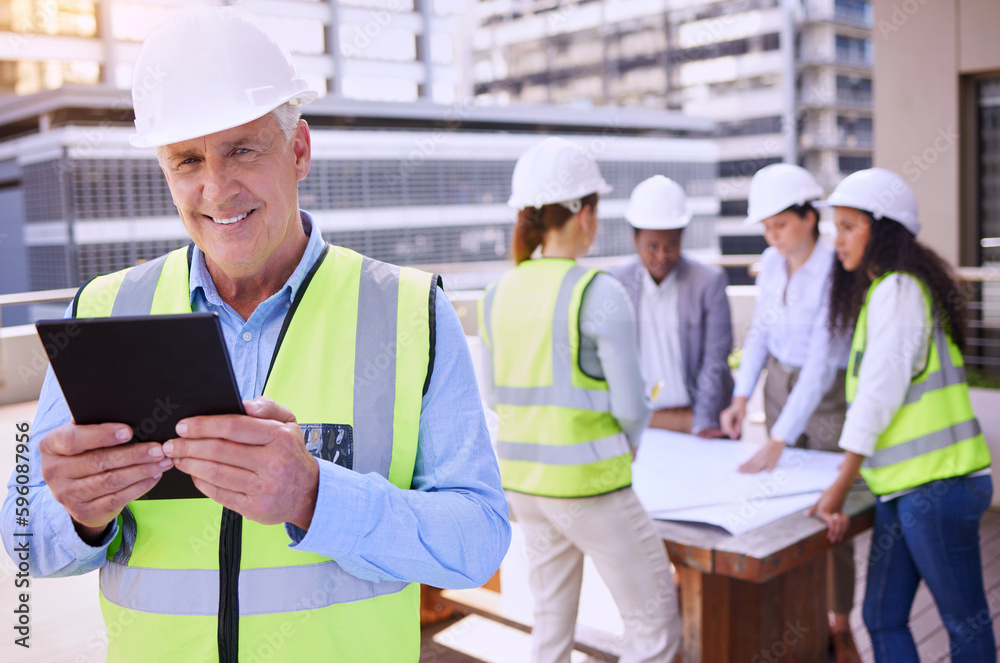 Running the entire operation on his tablet. a handsome mature male construction worker using a tablet while standing outside with his team in the background. Running the entire operation on his tablet. a handsome mature male construction worker using a tablet while standing outside with his team in the background.