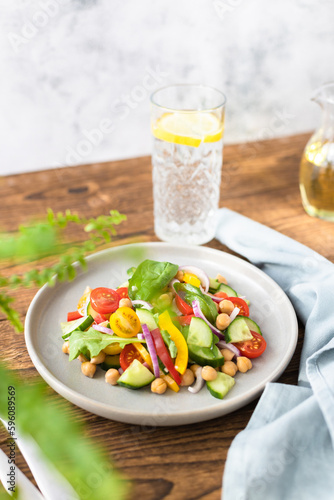 Salad of chickpeas and fresh vegetables and lettuce on a wooden table. Vegetarian food high in protein.