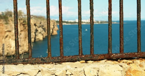 rusty fence rocks and sea at sunset