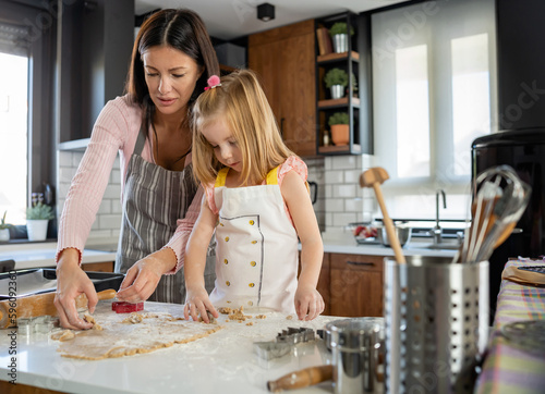 A child helps the mother in the Kitchen to bake sugar cakes. Early education and house chores.