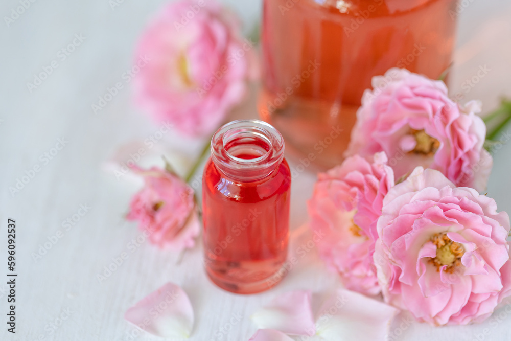 Concept of perfume with pure natural organic rose ingredient, essential oils. Glass bottles with flower herbal extract and elixir. Perfumery cosmetic toilet water fragrance, cream, skin care product Concept of perfume with pure natural organic rose ingredient, essential oils. Glass bottles with flower herbal extract and elixir. Perfumery cosmetic toilet water fragrance, cream, skin care product